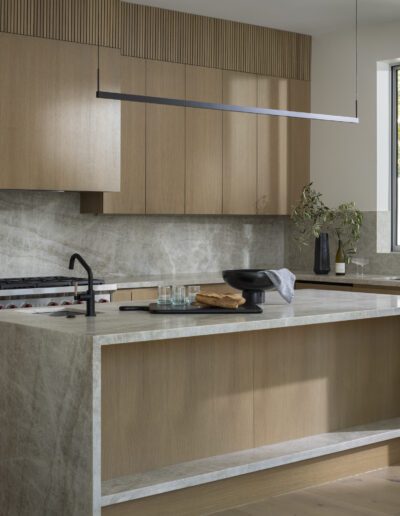 A modern kitchen with wood cabinets and marble counter tops.