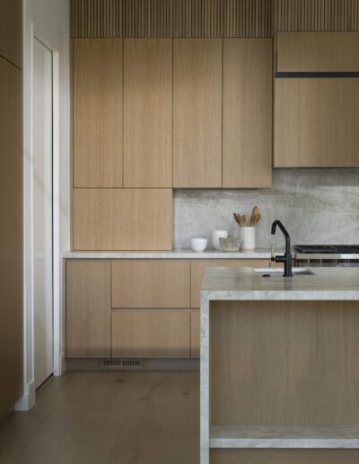 A modern kitchen with wood cabinets and marble counter tops.
